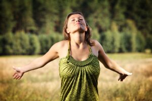 Eine Person entspannt sich in der Natur – bewusste Pausen helfen gegen Burnout.