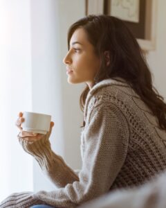 Eine Frau im warmen Morgenlicht, die ruhig schaut. Die Aufwachende