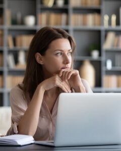 Frau am Laptop sitzend. Sie scheint alles im Griff zu haben, und doch funktioniert sie nur.
